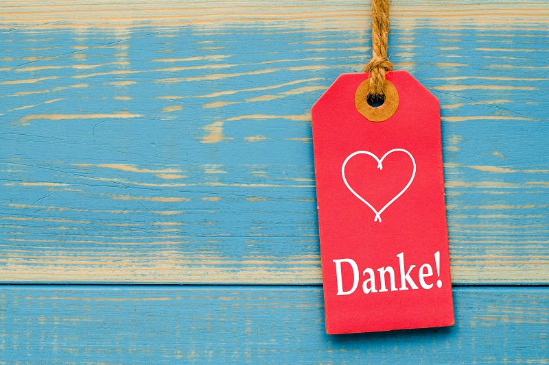 roter Herz-Anhänger mit Danke auf türkiser shabby Holzwand 